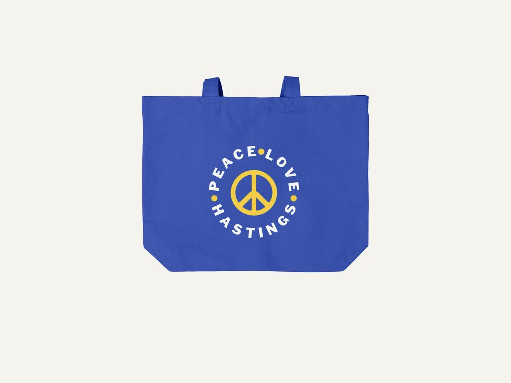 Peace Love Hastings gold peace sign on a royal blue cotton canvas tote bag.
